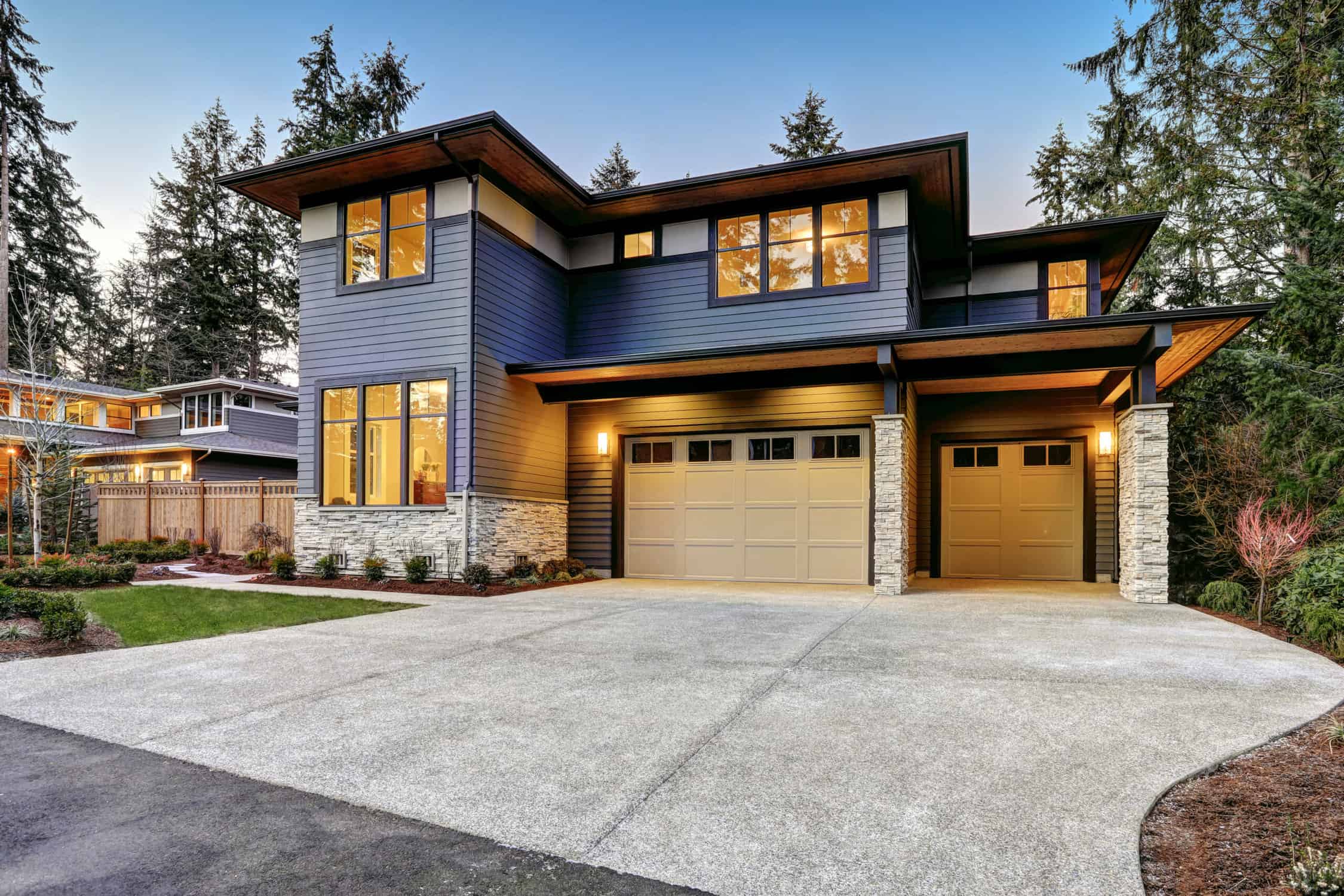 Modern style home with two car garage framed by blue siding and natural stone wall trim.