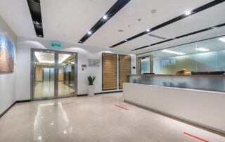 A commercial office hall with a reception desk, glass doors and a picture on the wall. Red line markings for social distance - seasonal touch-ups